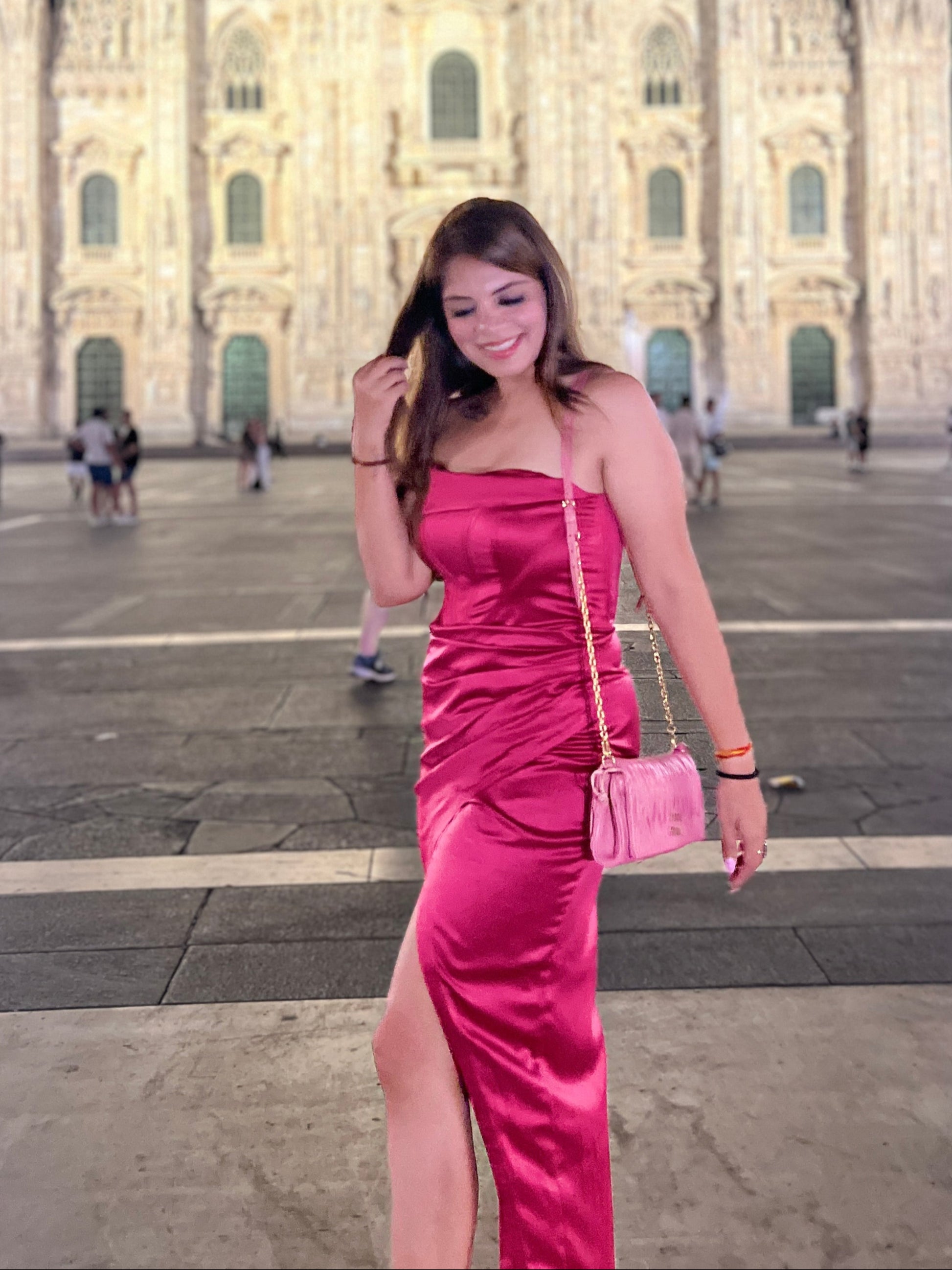 Woman wearing a fuchsia satin bodycon dress with side slit, styled for an elegant evening look.