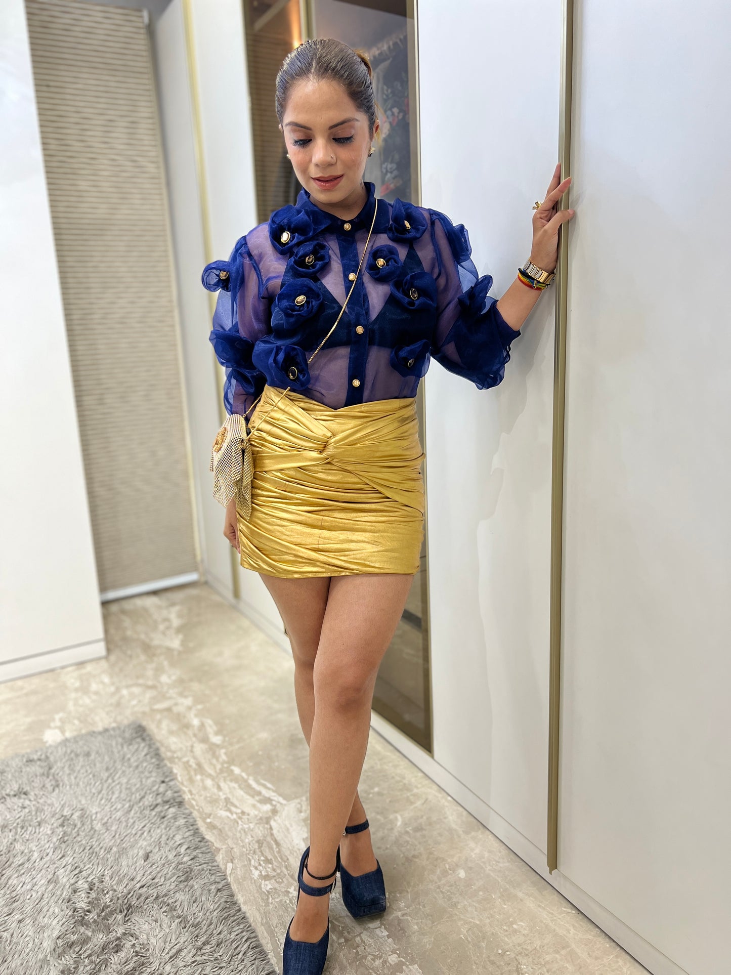 Model wearing navy blue 3D floral organza shirt styled with gold skirt and heels – fashion outfit idea