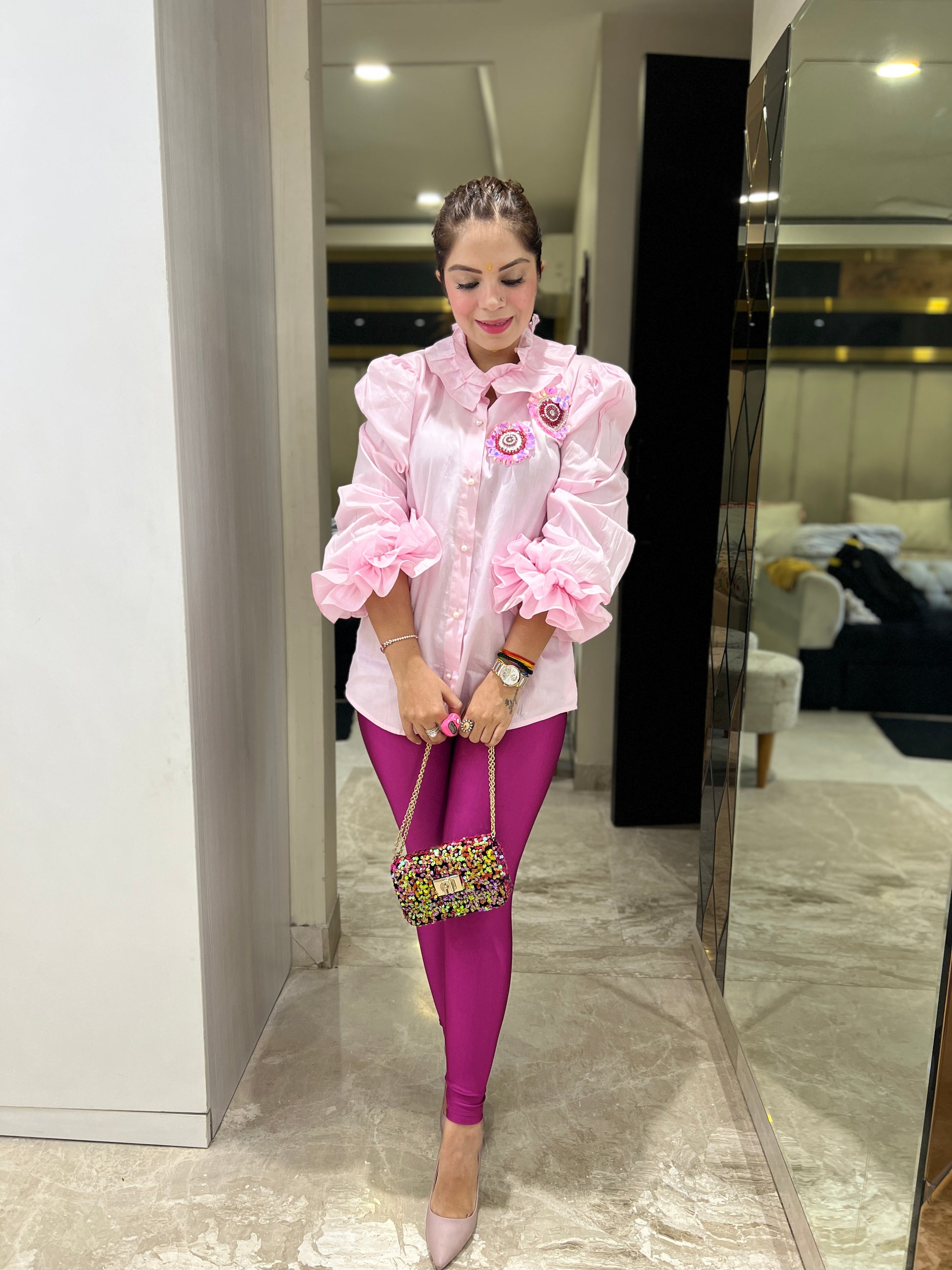 Woman wearing pink ruffled puff sleeve shirt with floral brooch detail – stylish statement top